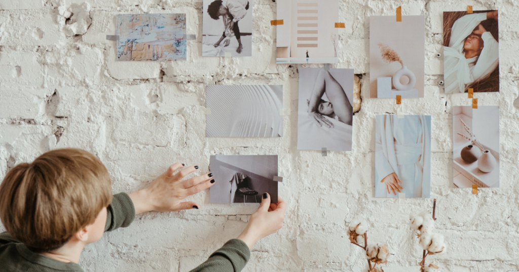 Person placing pictures on the wall for interior design inspiration