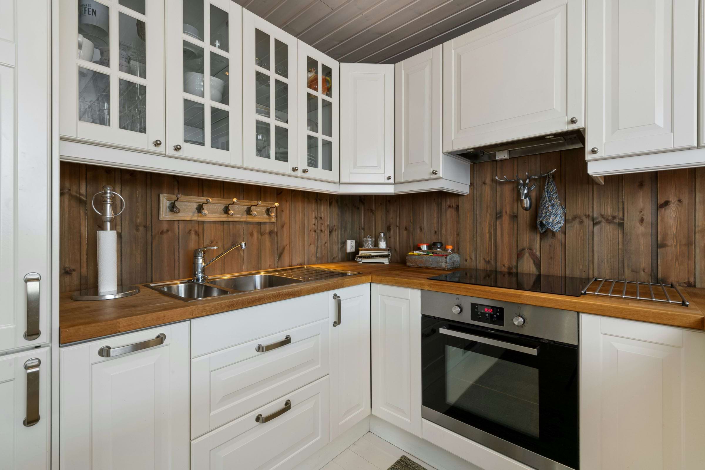 Kitchen interior with white cabinets and rustic wood backsplash and countertop.