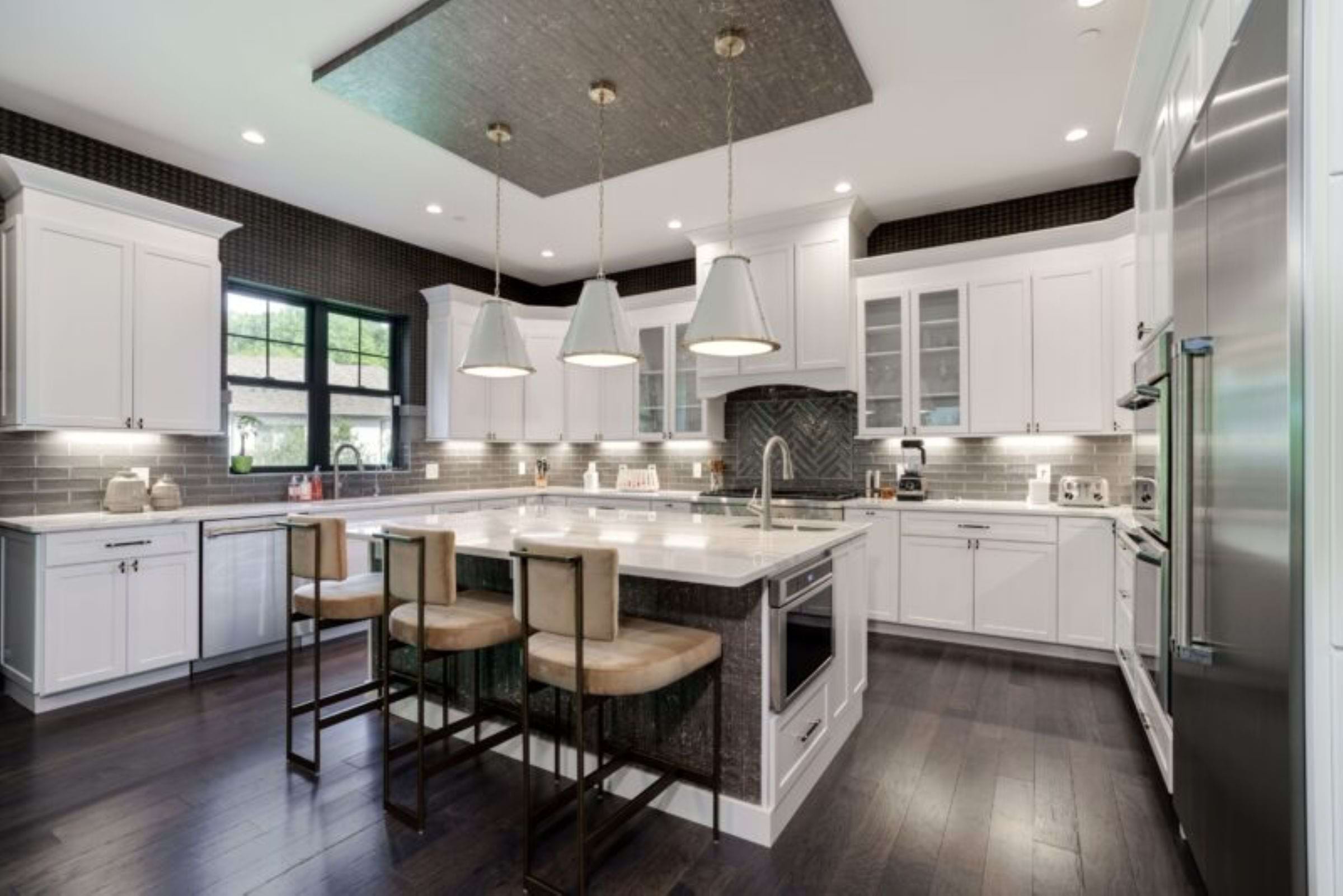 Kitchen interior featuring white cabinets and a gray floor, gray backsplash, and stainless steel appliances.