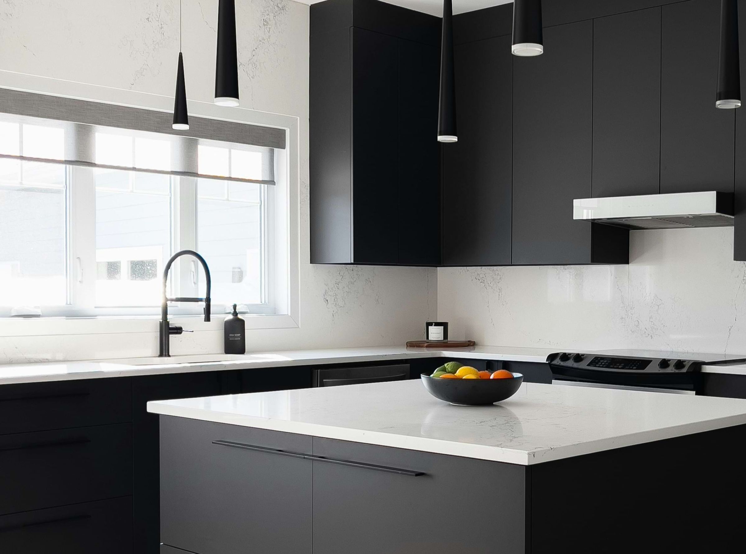 Interior of a kitchen featuring black cabinets and white countertops.