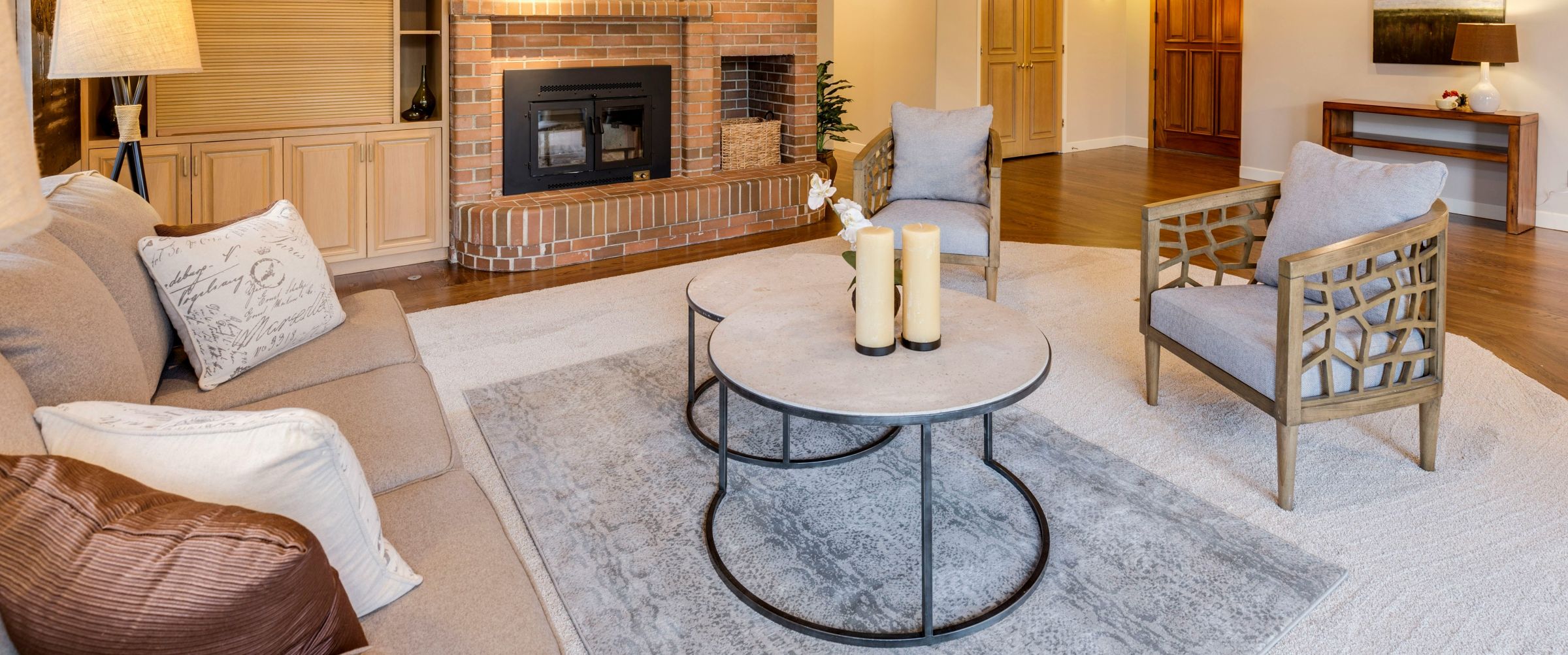 Interior of a living room featuring a brown color palette with chairs, sofa, and rugs.