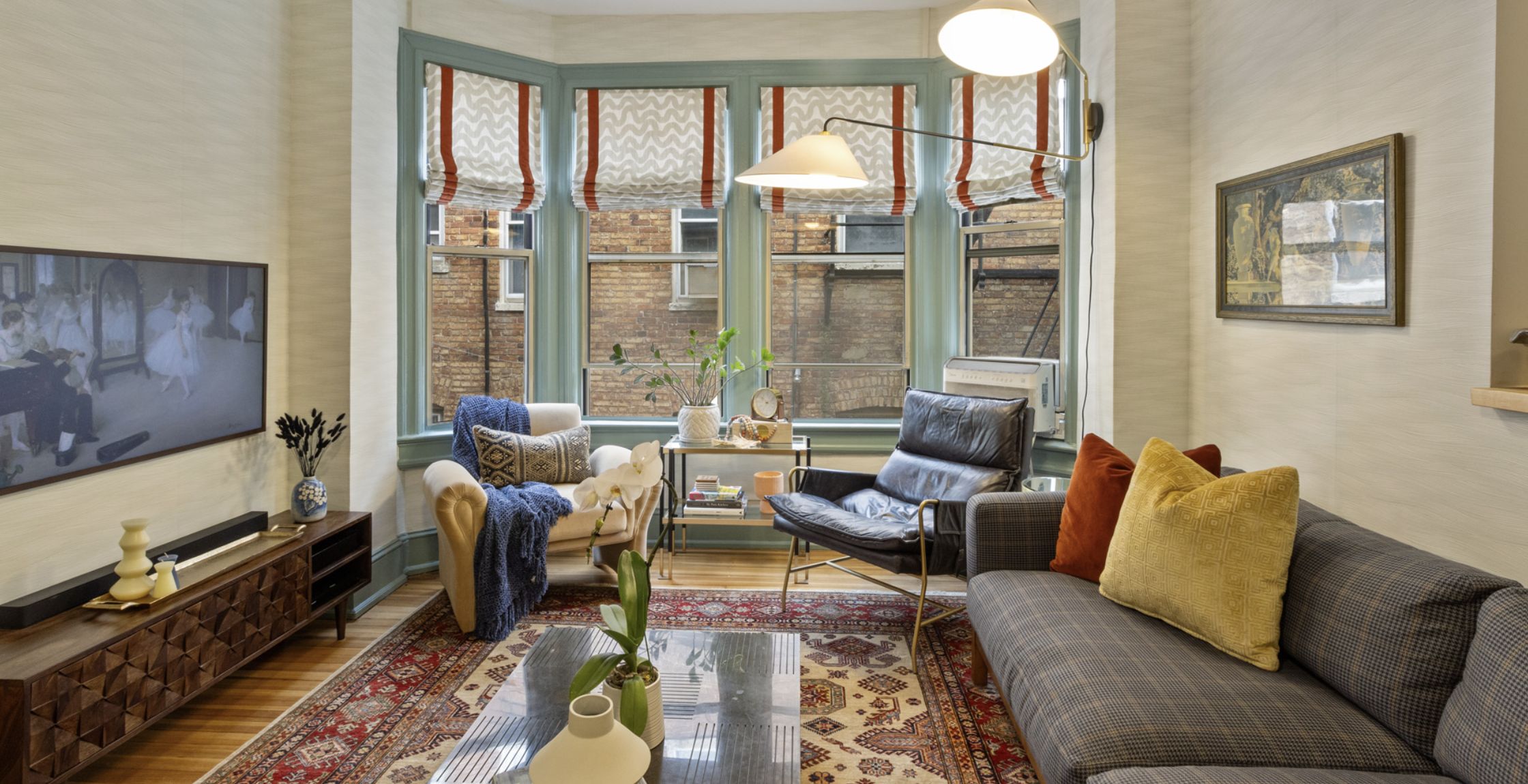 Open sitting area with large windows on one wall, furniture sits in front of the windows and on one wall, and a television hangs on the third wall.