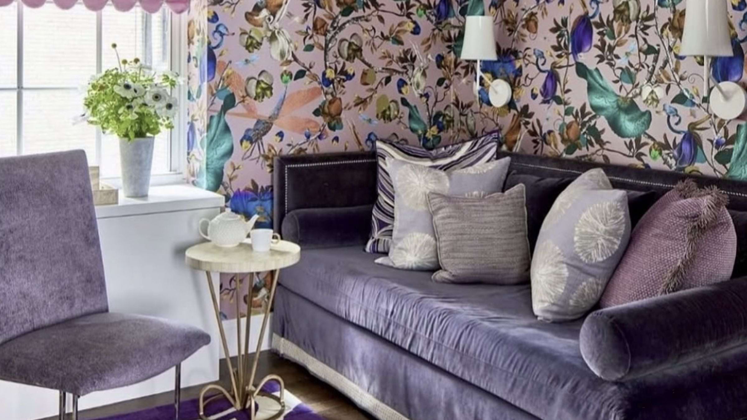 A deep purple couch against a wall with coordinating wallpaper in various purple hues.
