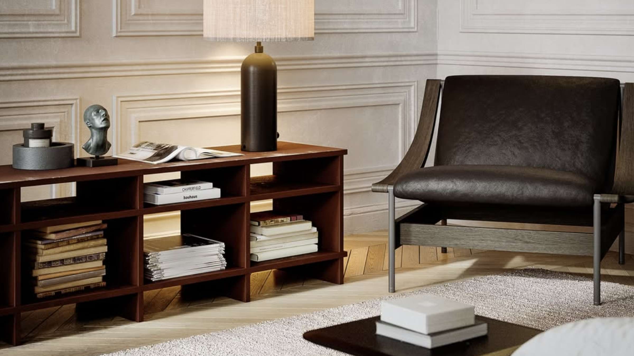 A sitting area with a leather chair that sits next to a wooden table with a reading lamps and various books and magazines.